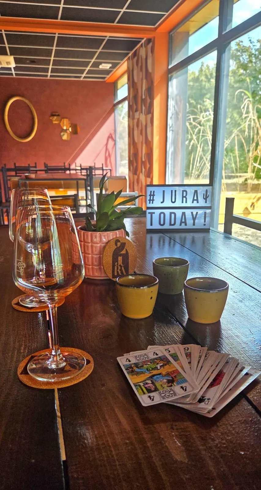 Une grande table du JuRa préparée avec des verres, des cartes à jouer et de la petite vaisselle