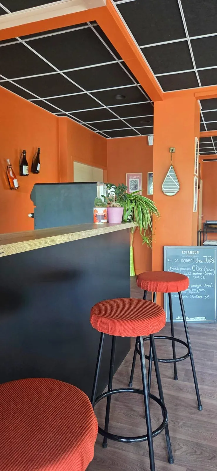 Le comptoir noir et ses tabourets orange dans la salle du JuRa